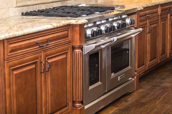 stainless steel oven and stove top between wooden cabinetry