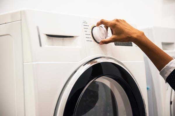 a woman turning the knob on her washing machine